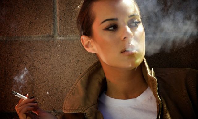 2 Irrtümer des Rauchens: Hübsche Frau raucht genüsslich eine Zigarette