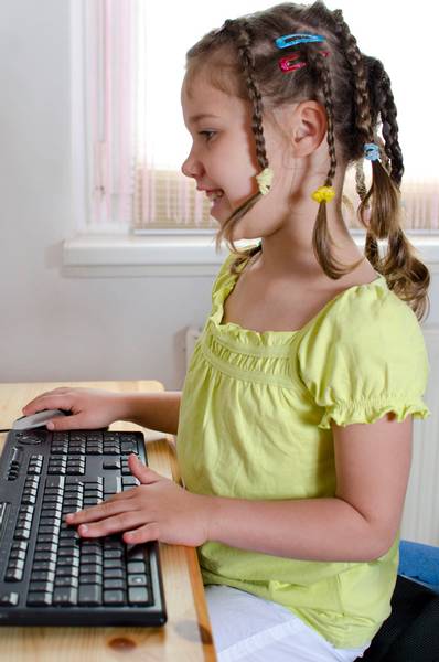 Mädchen sitzt am Schreibtisch mit Tastatur